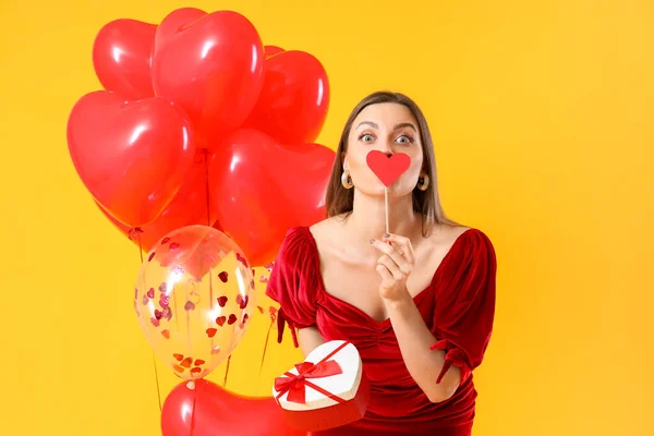 Schöne Junge Frau Mit Geschenk Und Luftballons Auf Farbigem Hintergrund — Stockfoto