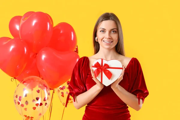 Schöne Junge Frau Mit Geschenk Und Luftballons Auf Farbigem Hintergrund — Stockfoto