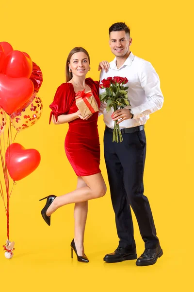 Glückliches Junges Paar Mit Geschenk Und Blumen Auf Farbigem Hintergrund — Stockfoto