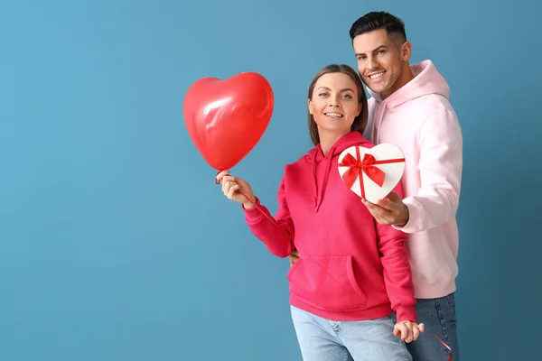 Glückliches Junges Paar Mit Geschenk Und Luftballon Auf Farbigem Hintergrund — Stockfoto