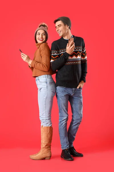 Happy Young Couple Warm Sweaters Phones Color Background — 스톡 사진