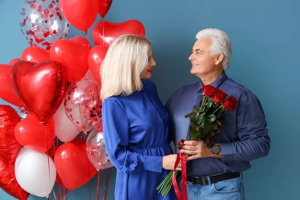 Happy Mature Couple Flowers Balloons Color Background Valentine Day Celebration — стоковое фото