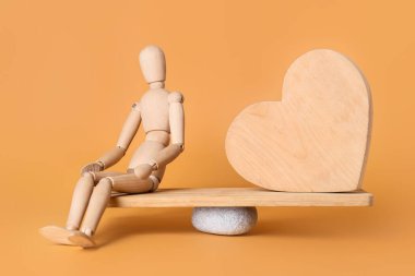 Manken ve tahta kalp renk arka planına karşı tahtanın üzerinde. Denge kavramı