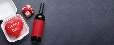 Lezzetli bento keki ve Sevgililer Günü hediyesi. Karanlık arka planda bir şişe şarap ve mesaj için yer var.