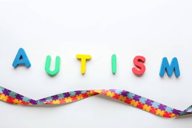 Kelime AUTISM ve açık arkaplanda farkındalık kurdelesi