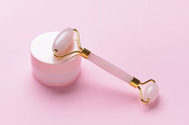 Renk arkaplanında kozmetik kremi olan yüz masajı silindiri