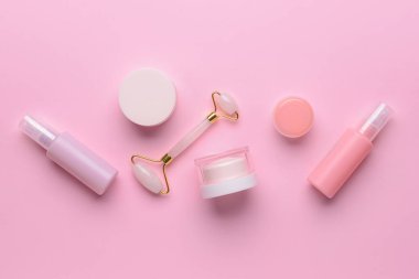 Renk arkaplanında kozmetik ürünleri olan yüz masajı silindiri