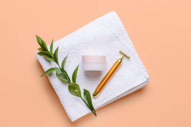 Yüz masajı silindiri. Kozmetik krem ve arka planda havlu.