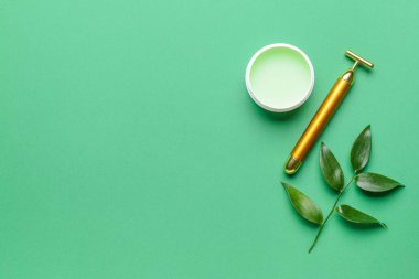 Renk arkaplanında kozmetik kremi olan yüz masajı silindiri