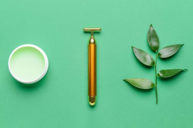 Renk arkaplanında kozmetik kremi olan yüz masajı silindiri