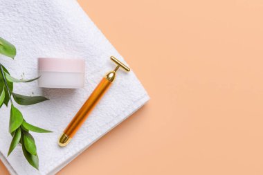 Yüz masajı silindiri. Kozmetik krem ve arka planda havlu.