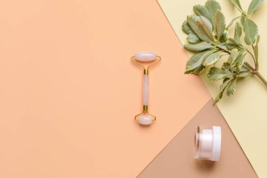 Renk arkaplanında kozmetik kremi olan yüz masajı silindiri