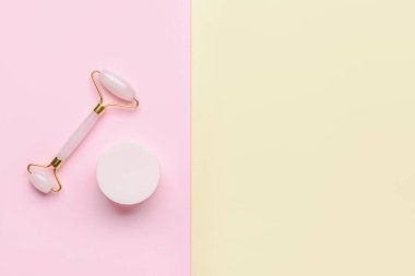 Renk arkaplanında kozmetik kremi olan yüz masajı silindiri
