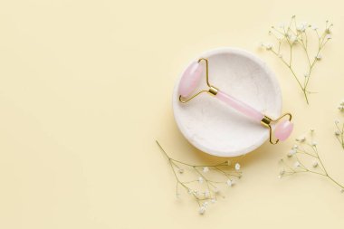 Hafif arka planda çiçekleri olan yüz masajı silindiri