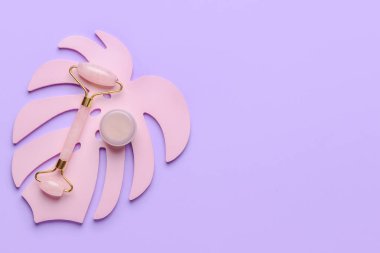 Renk arkaplanında kozmetik kremi olan yüz masajı silindiri