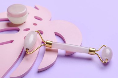 Renk arkaplanında kozmetik kremi olan yüz masajı silindiri