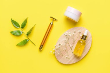 Renk arkaplanında kozmetik ürünleri olan yüz masajı silindiri