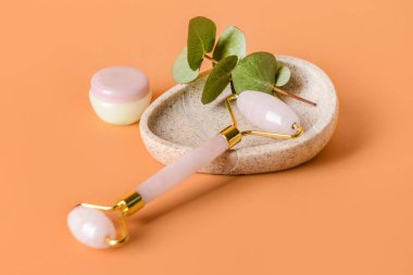 Renk arkaplanında kozmetik kremi olan yüz masajı silindiri