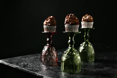 Koyu arkaplanda şarap bardakları olan lezzetli çikolatalı kekler.