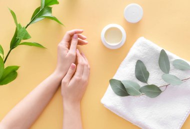 Kadın eli ve kozmetik krem kavanozu ve banyo havlusu.