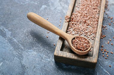 Renk arkaplanında keten tohumları olan tepsi ve kaşık