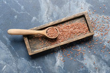 Renk arkaplanında keten tohumları olan tepsi ve kaşık