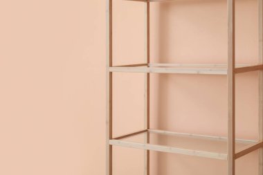 Pembe duvarın yanındaki boş ahşap raf ünitesi.