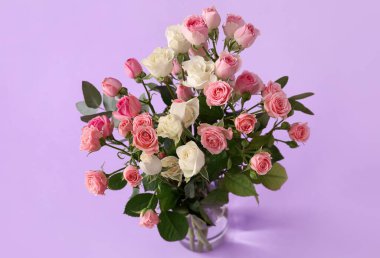 Mor arka planda bir buket güzel gül olan vazo.