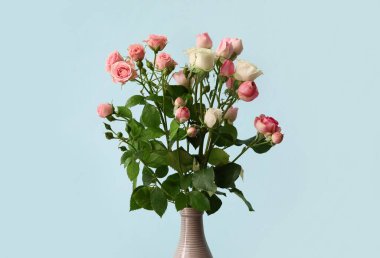 Mavi arka planda bir buket güzel gül olan vazo.