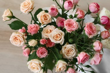 Masanın üzerinde bir buket gül olan vazo.