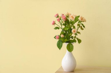 Vazo dolusu güzel güller ahşap masada.