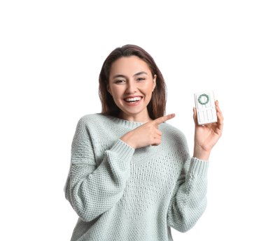 Gülümseyen genç kadın beyaz arka planda zencefilli kurabiyeye işaret ediyor.