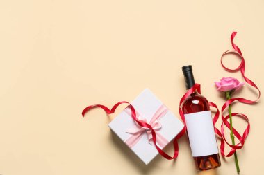 Bir şişe şarap, hediye ve arka planda gül çiçeği.