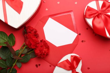 Sevgililer günü için hediye kutuları. Kırmızı arka planda güller ve zarf.