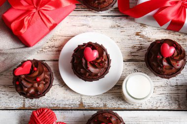 Sevgililer günü için lezzetli çikolatalı kekler ve hafif ahşap arka planda bir bardak süt.