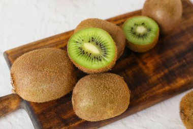 Açık arkaplanda taze olgun kivi olan tahta, yakın plan.