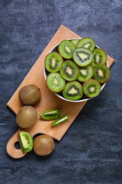 Koyu arkaplanda taze kesilmiş kivi kasesi.