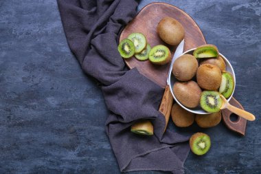 Koyu arkaplanda taze olgun kivi olan bir kase.