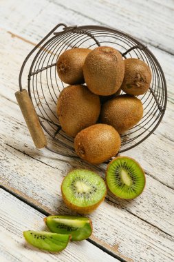 Açık ahşap zemin üzerinde taze olgun kivi olan sepet, yakın plan.