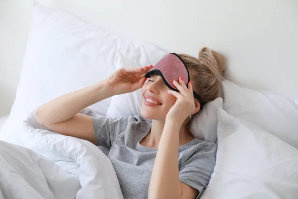 Beautiful Young Woman Taking Sleeping Mask Bed — стоковое фото