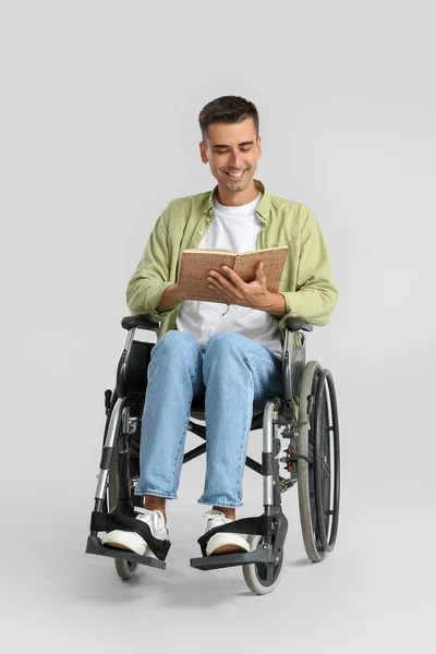 Young Man Wheelchair Reading Book Light Background — Zdjęcie stockowe