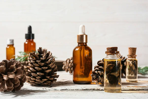 Bottles Essential Oil Pine Cones Light Wooden Background — Stock Photo, Image