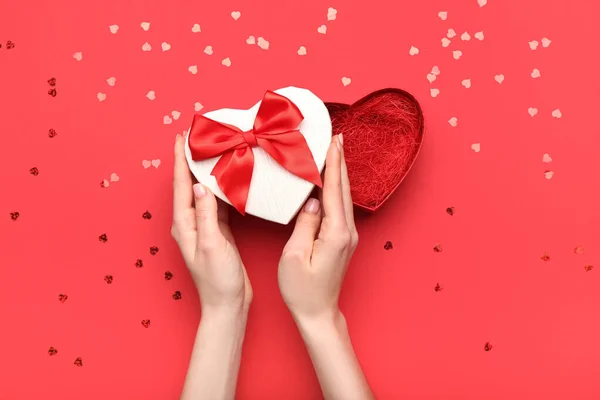 赤い背景にバレンタインデーのギフトボックスを持つ女性の手 — ストック写真