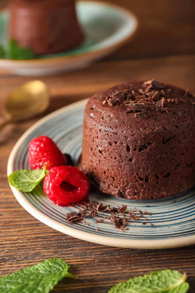 Lezzetli lav keki şekerlemeli tabak ve ahşap arka planda ahududu, yakın plan.