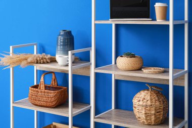 Dekorlu raf ünitesi, dizüstü bilgisayar ve mavi duvarın yanında bir fincan kahve.