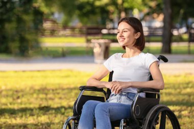 Parkta fiziksel engelli genç bir kadın var.