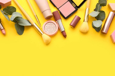 Sarı arka planda dekoratif kozmetik ve okaliptüs dalları