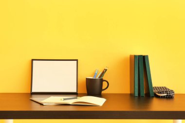 Renk duvarının yanındaki masada kırtasiye malzemeleri ve boş fotoğraf çerçevesi