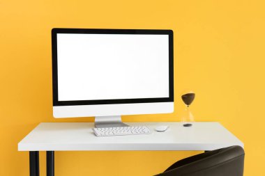 Renkli duvarın yanında modern bilgisayar ve kum saati olan işyeri