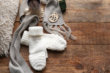 Sıcak eldivenler, eşarp ve ahşap arka planda bir fincan çay.